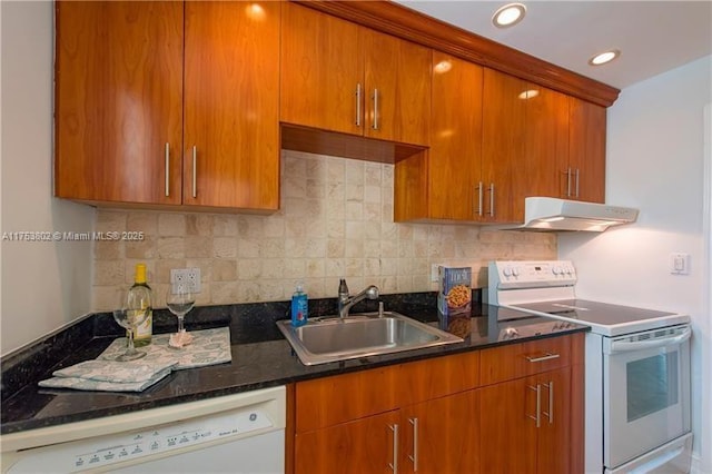 kitchen with tasteful backsplash, white appliances, a sink, and under cabinet range hood