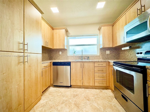 kitchen with appliances with stainless steel finishes, a sink, backsplash, and light brown cabinetry