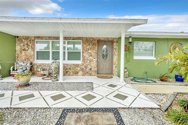 view of exterior entry featuring stone siding and stucco siding