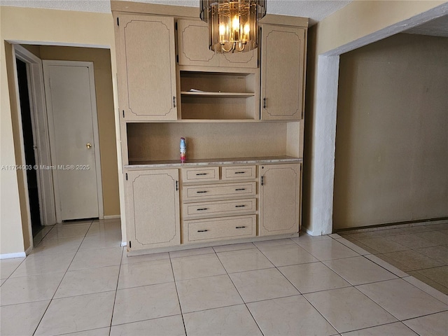 kitchen with light tile patterned floors, open shelves, baseboards, and a notable chandelier