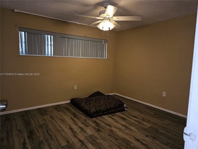 empty room featuring ceiling fan, baseboards, and wood finished floors