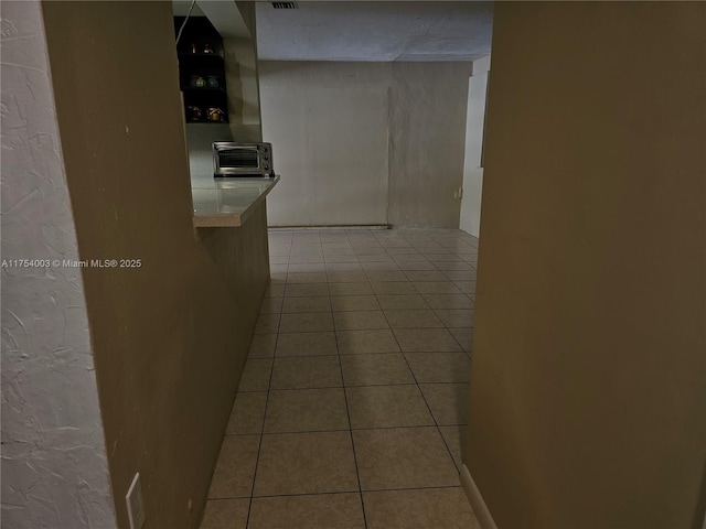 hallway with a toaster, visible vents, and tile patterned floors