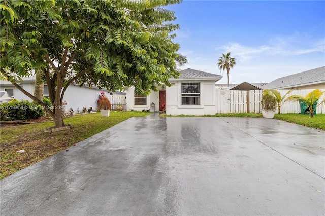 view of front of home with fence, driveway, and stucco siding