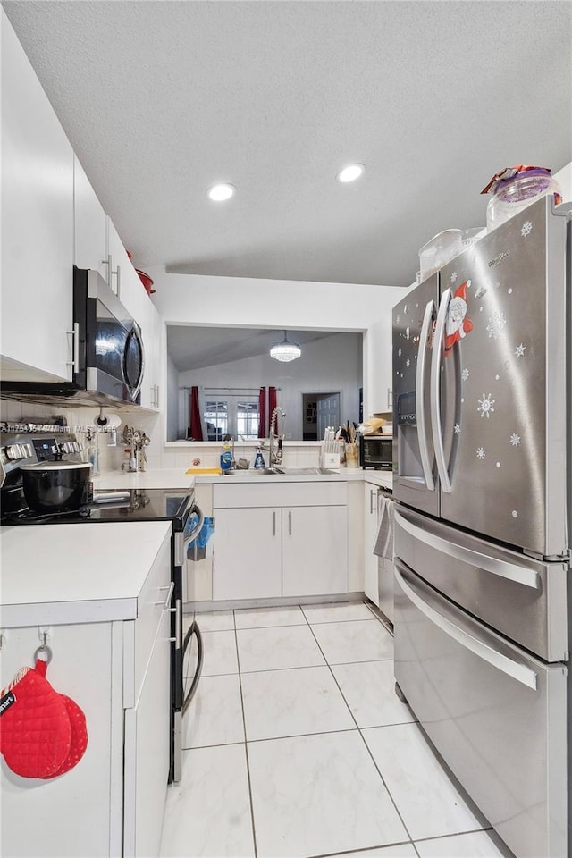 kitchen featuring light tile patterned floors, light countertops, appliances with stainless steel finishes, white cabinetry, and a sink