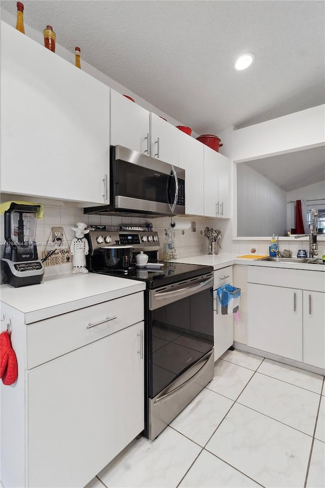 kitchen with decorative backsplash, appliances with stainless steel finishes, light countertops, white cabinetry, and a sink