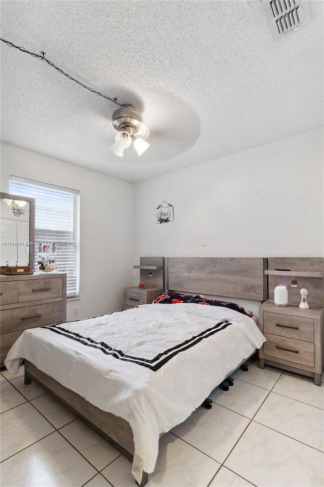 bedroom with a ceiling fan, visible vents, and a textured ceiling