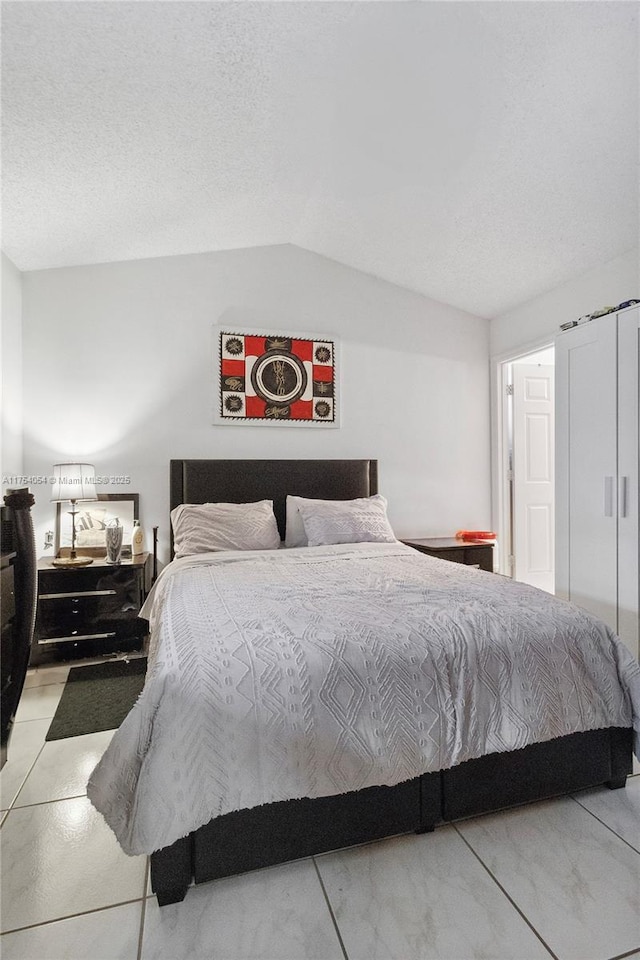 bedroom with lofted ceiling and a textured ceiling