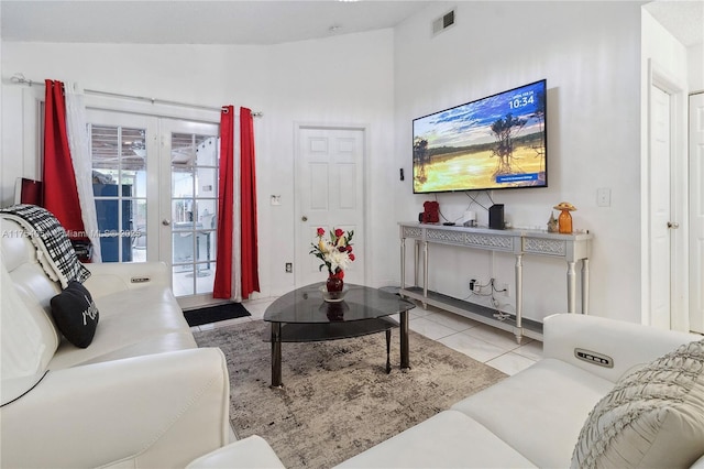 living area featuring lofted ceiling, french doors, light tile patterned flooring, and visible vents