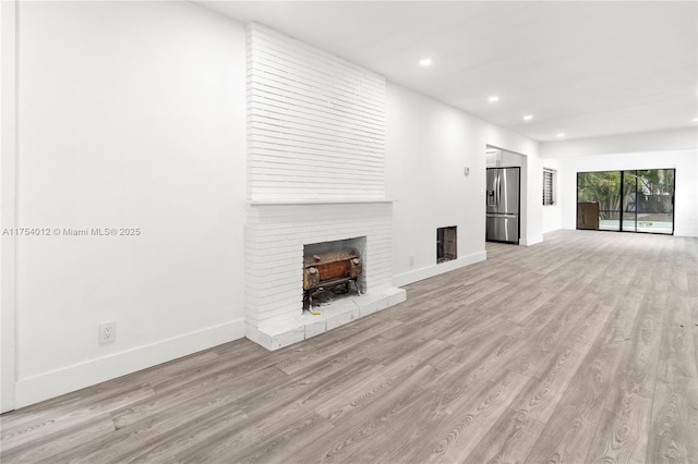 unfurnished living room with recessed lighting, light wood-style flooring, and baseboards