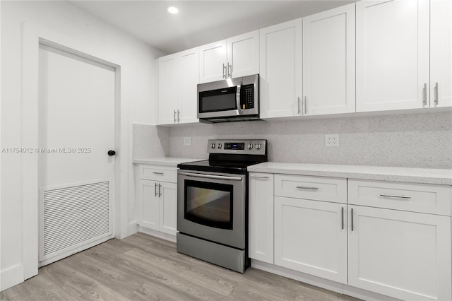 kitchen with visible vents, decorative backsplash, appliances with stainless steel finishes, light wood-style floors, and white cabinets