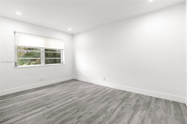 empty room featuring baseboards, wood finished floors, and recessed lighting