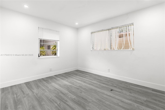 empty room with baseboards, wood finished floors, and recessed lighting