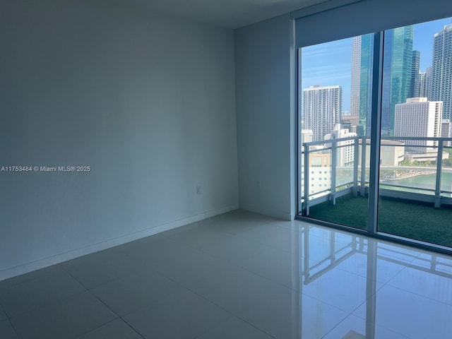 empty room featuring a city view, baseboards, and tile patterned floors