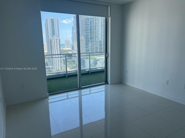 tiled empty room featuring baseboards and a city view