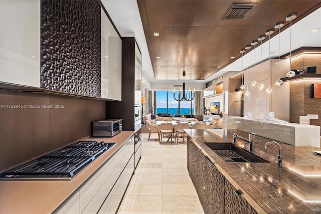 kitchen featuring a toaster, visible vents, oven, gas stovetop, and a sink