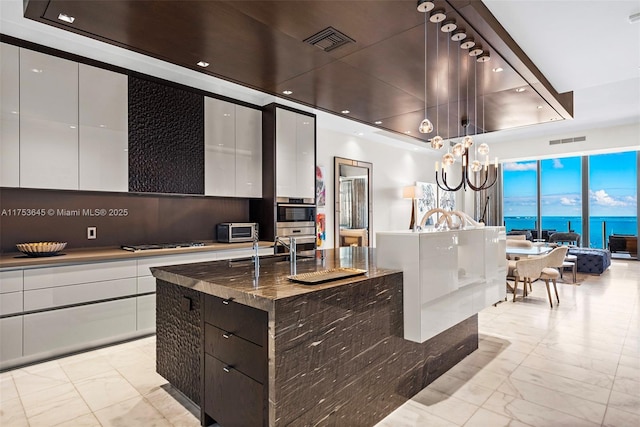 kitchen with a tray ceiling, modern cabinets, gas cooktop, and visible vents