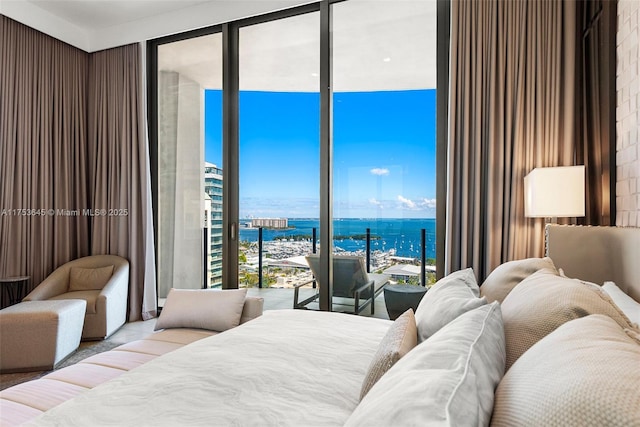 bedroom featuring a wall of windows, access to exterior, and a water view