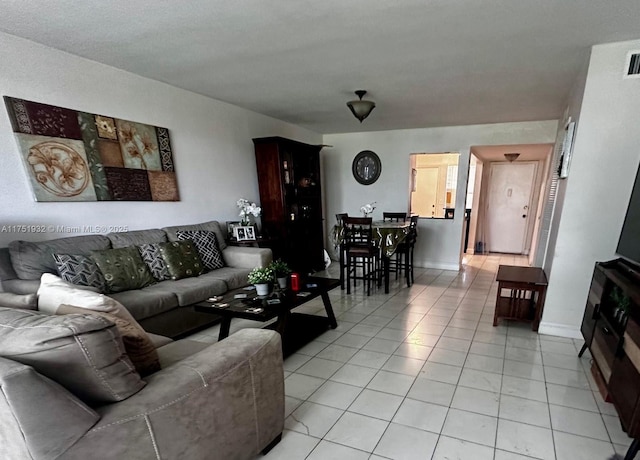 living area featuring light tile patterned floors, visible vents, and baseboards