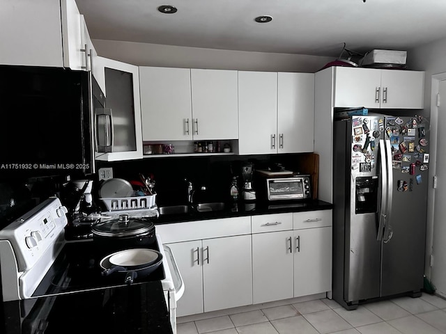 kitchen with stainless steel fridge, range with electric cooktop, dark countertops, black microwave, and a sink