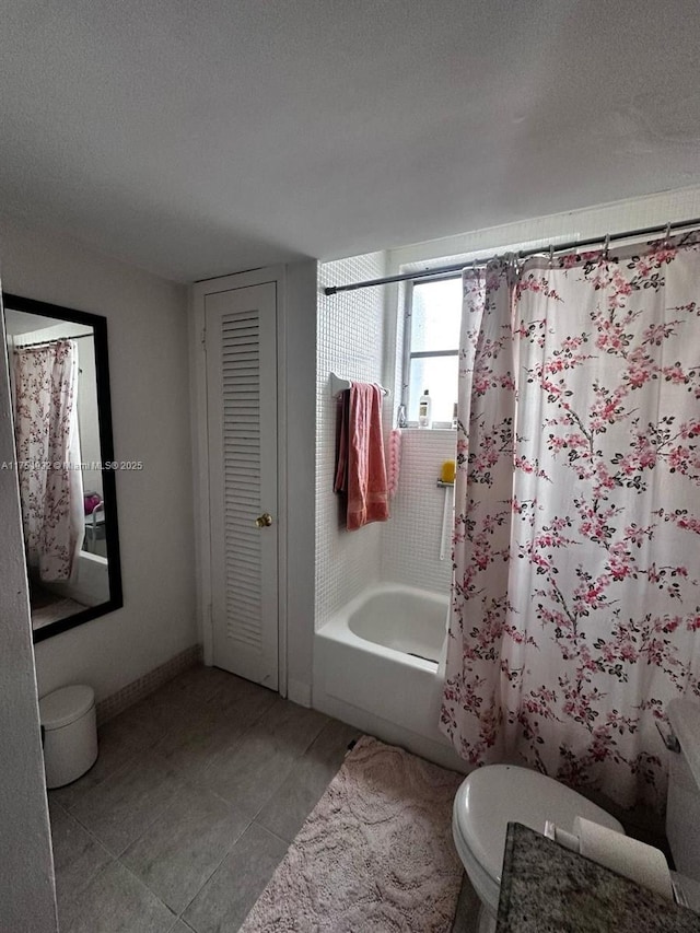 full bathroom featuring toilet, tile patterned floors, a textured ceiling, and shower / tub combo with curtain