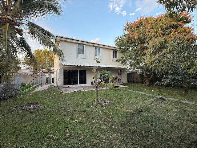 rear view of property with stucco siding, a fenced backyard, and a yard