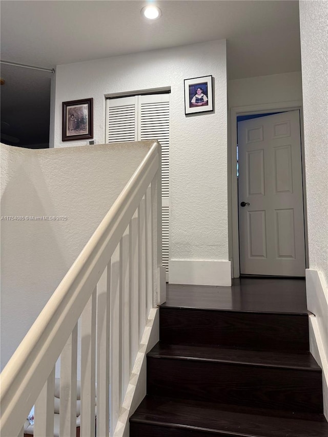 stairs featuring wood finished floors and a textured wall