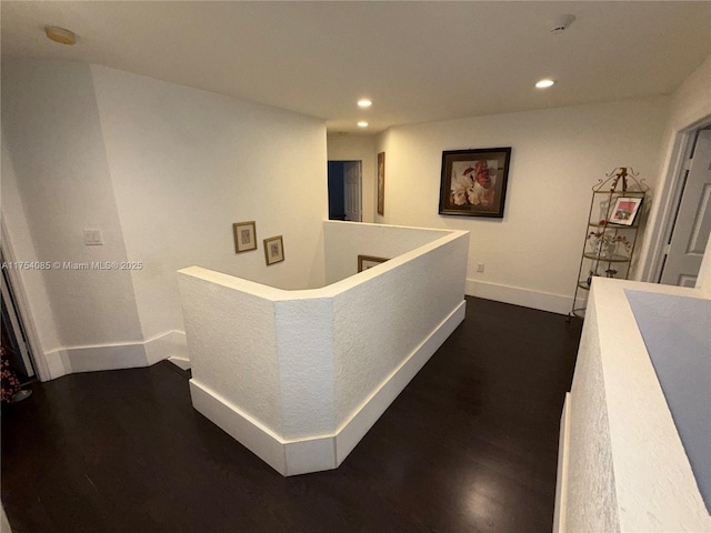 corridor with dark wood-style floors, baseboards, an upstairs landing, and recessed lighting