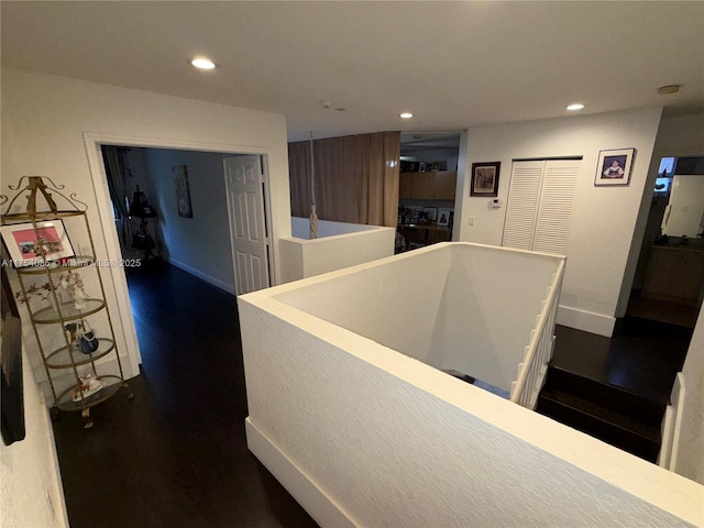 hallway featuring recessed lighting, baseboards, dark wood finished floors, and an upstairs landing