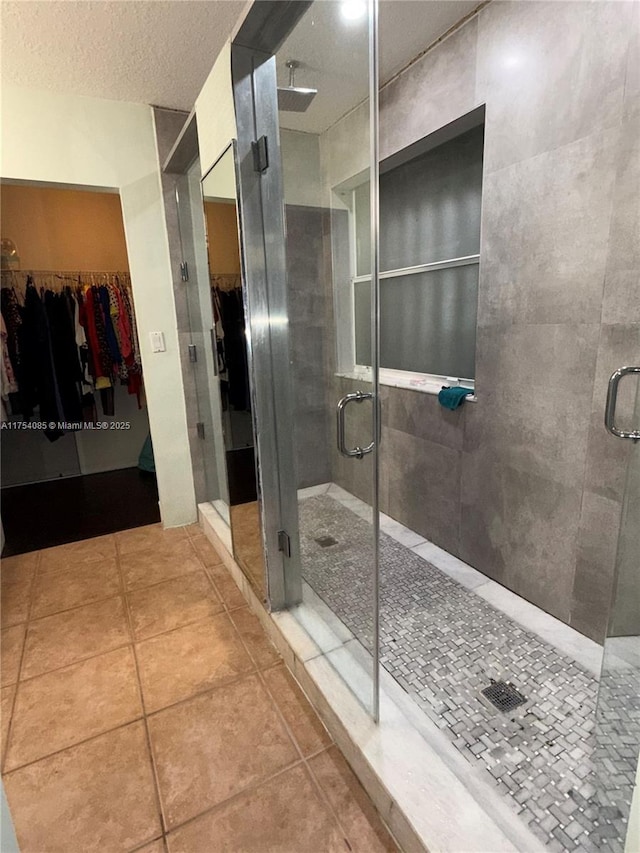 bathroom featuring a shower stall, a textured ceiling, and tile patterned floors