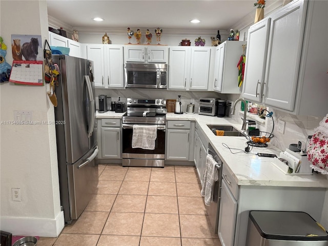 kitchen featuring light tile patterned floors, crown molding, stainless steel appliances, and a sink