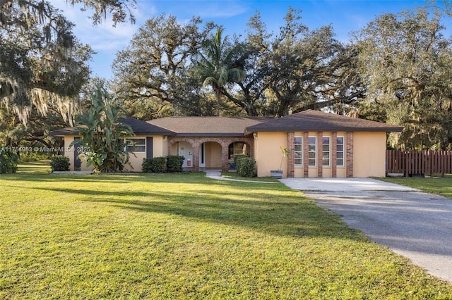 view of front facade featuring driveway, a front yard, fence, and stucco siding