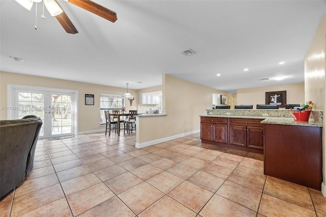 kitchen with light stone countertops, light tile patterned floors, open floor plan, and french doors