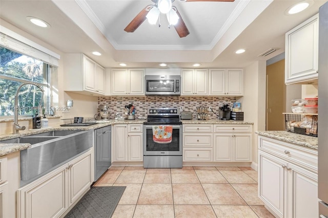 kitchen with light tile patterned floors, stainless steel appliances, tasteful backsplash, and a raised ceiling