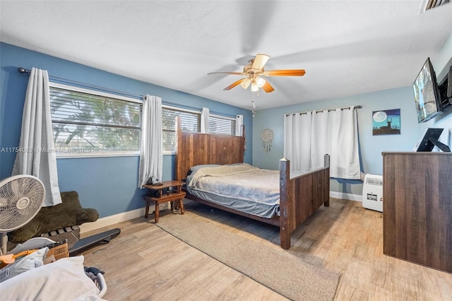 bedroom featuring ceiling fan, wood finished floors, visible vents, and baseboards