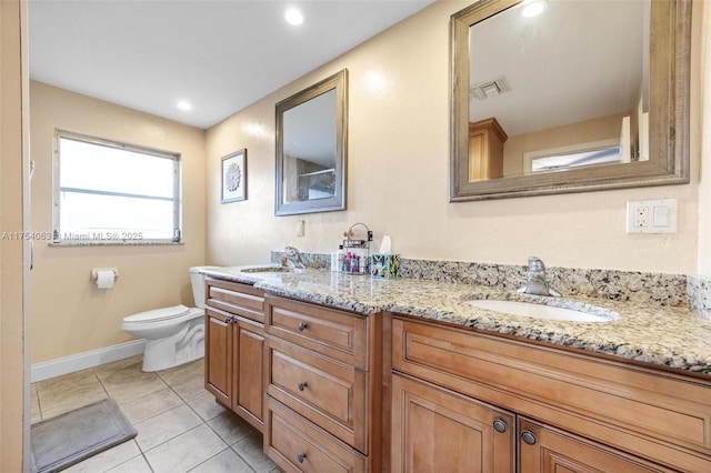 bathroom with double vanity, tile patterned flooring, a sink, and toilet