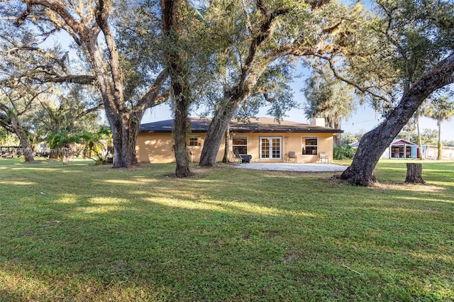 rear view of house with a patio, a chimney, a lawn, and stucco siding