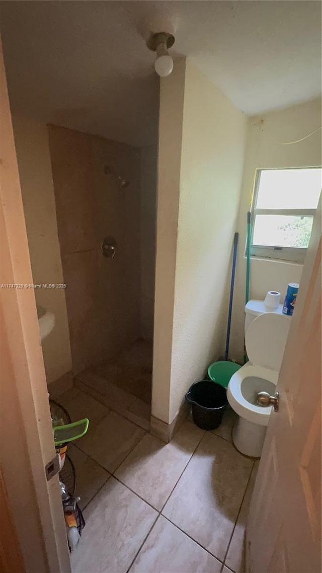 bathroom with a stall shower, toilet, and tile patterned floors