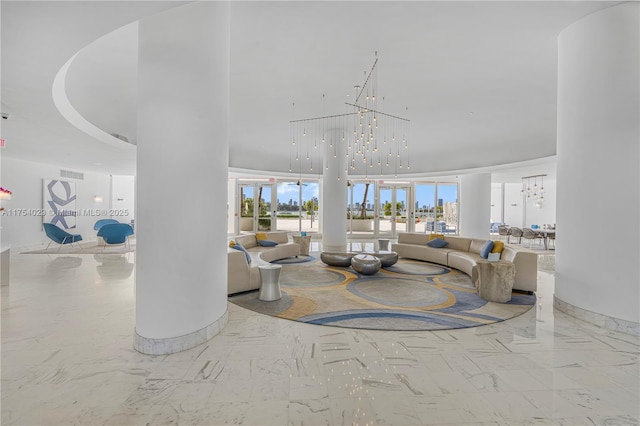 living area featuring a chandelier, marble finish floor, visible vents, and a towering ceiling