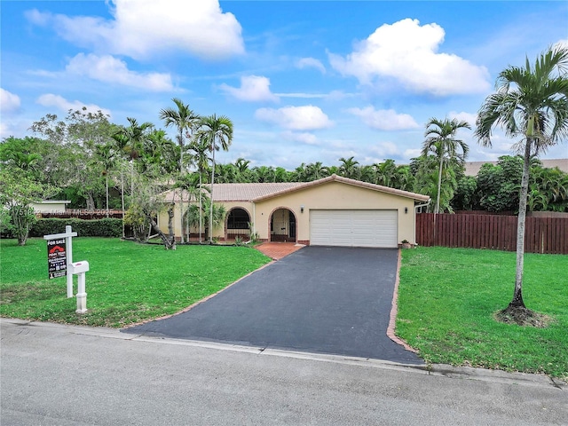 view of front facade with aphalt driveway, an attached garage, fence, stucco siding, and a front lawn