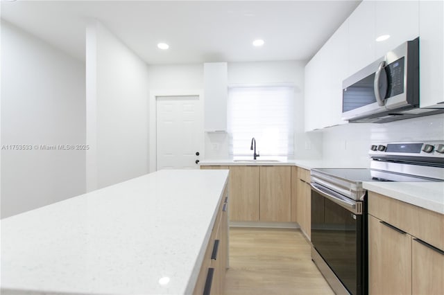 kitchen featuring light brown cabinets, modern cabinets, appliances with stainless steel finishes, and light countertops