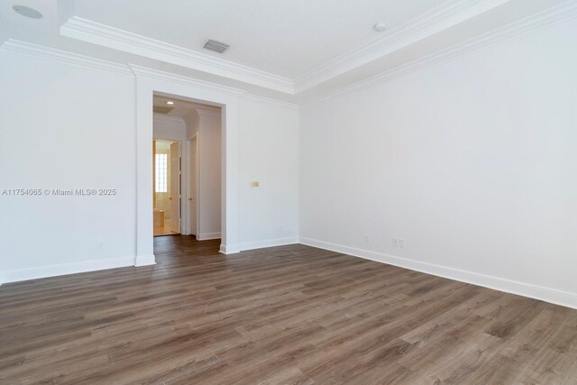 unfurnished room with baseboards, visible vents, crown molding, and wood finished floors