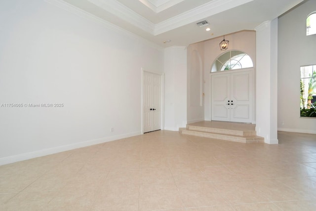 entrance foyer featuring baseboards, ornamental molding, visible vents, and a towering ceiling