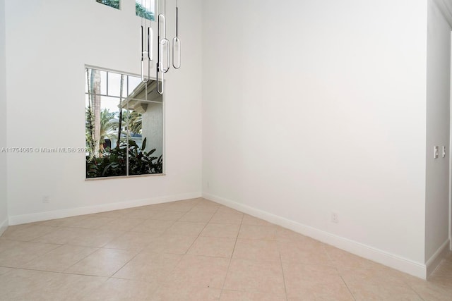 spare room with baseboards, a towering ceiling, and light tile patterned floors