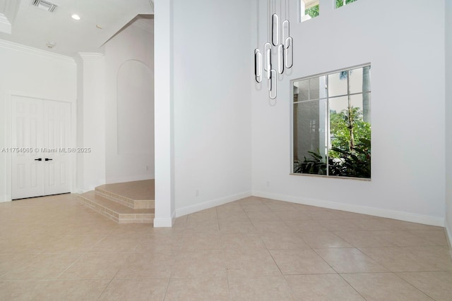 empty room with baseboards, a towering ceiling, visible vents, and light tile patterned floors