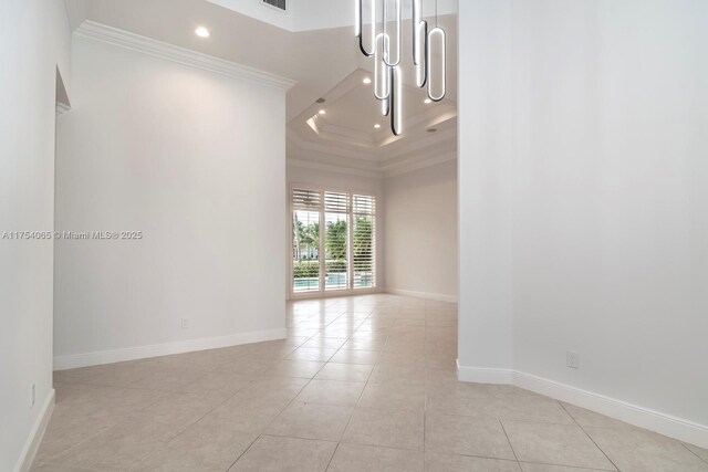 spare room with a high ceiling, light tile patterned floors, crown molding, and baseboards