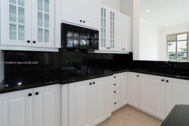 kitchen featuring a sink, white cabinets, tasteful backsplash, light tile patterned floors, and black appliances