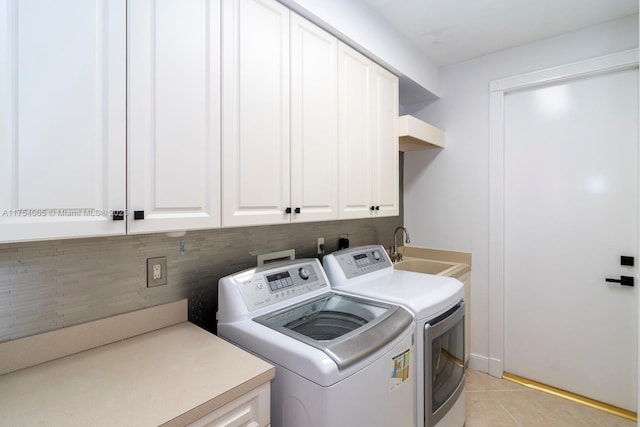 laundry area with cabinet space, a sink, separate washer and dryer, and light tile patterned floors