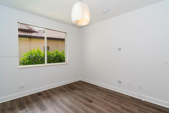 spare room with baseboards and wood finished floors