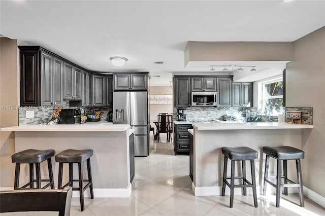 kitchen featuring appliances with stainless steel finishes, a peninsula, and a kitchen bar