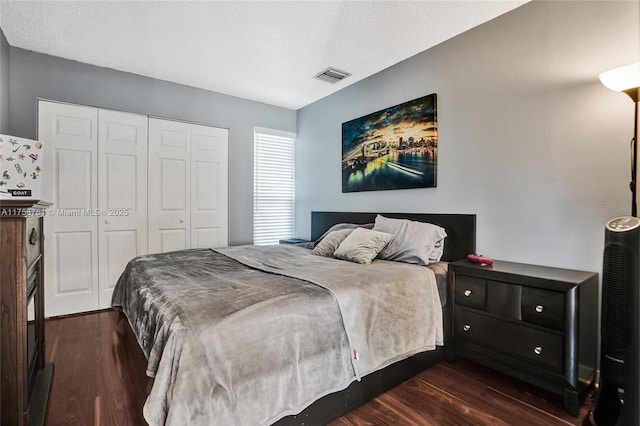 bedroom with dark wood-style flooring, a closet, and visible vents